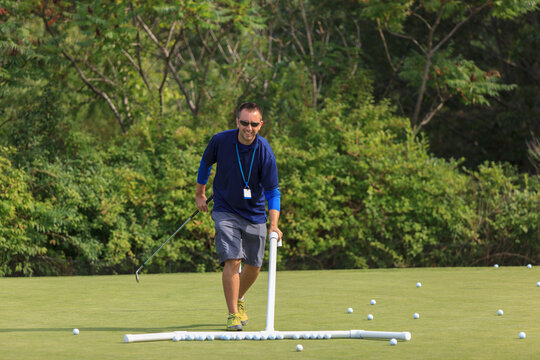 Assistant at a golf course gathering balls for play