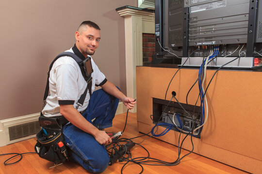 Cable installer working in a home behind the TV