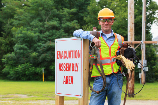 Communications engineer with climbing equipment and tool belts at evacuation assembly area