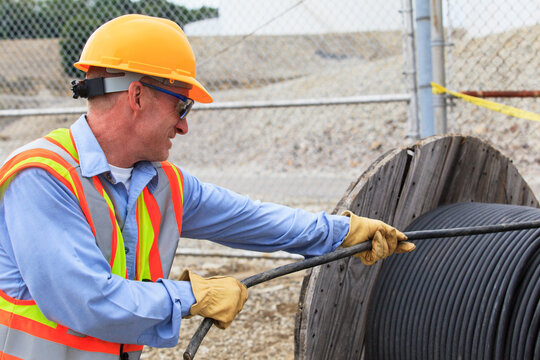 Electrical engineer pulling power cable from reel