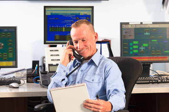 Electrical engineer in central operating command room at power station talking on phone