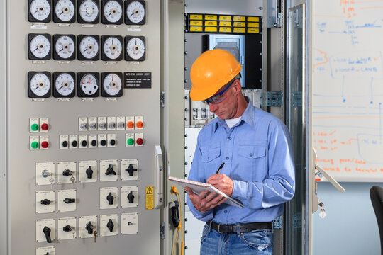Electrical engineer inspecting power plant controls in central operations room of power plant