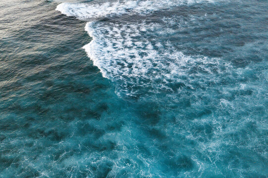 Aerial view of crashing ocean waves with white foam and turquoise water ripples at Siargao Island in General Luna, Caraga, Philippines.