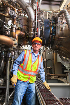 Engineer at fuel injection stage of gas turbine which drives generators in power plant while