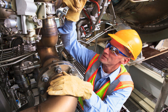 Engineer at turbine stage of gas turbine which drives generators in power plant while turbine is