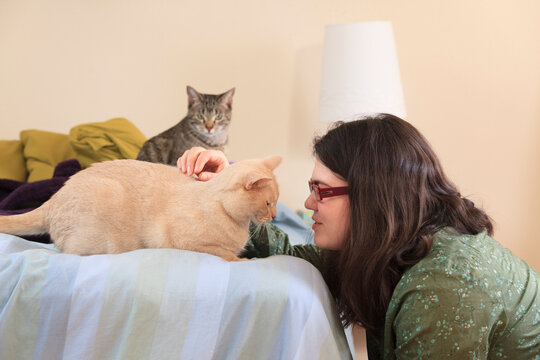 Woman with Asperger syndrome playing with her pet cats