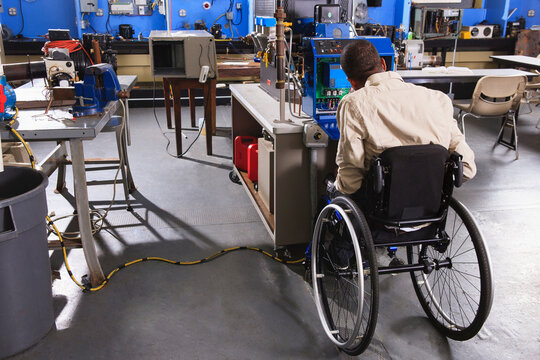 Student in wheelchair studying furnace electronic control system in HVAC classroom
