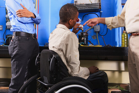 Instructor discussing condenser coil on refrigeration unit with student in wheelchair