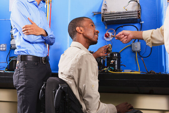 Instructor discussing condenser coil on refrigeration unit with student in wheelchair