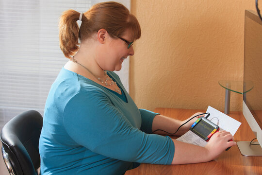 Woman who is legally blind reviewing government rules on blindness with a magnifier
