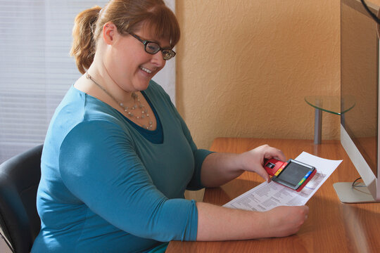 Woman who is legally blind reviewing government rules on blindness with a magnifier