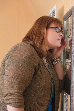 Woman who is legally blind checking her makeup at a mirror in her home