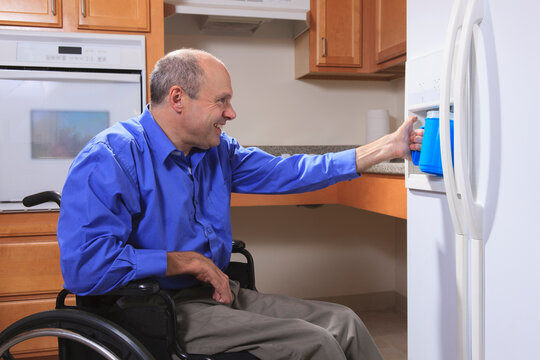 Man with Friedreich's Ataxia and deformed hands using the water dispenser in his refrigerator