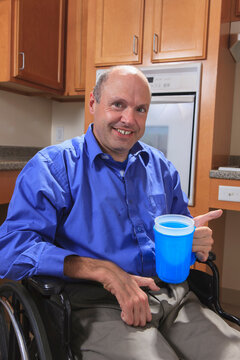 Man with Friedreich's Ataxia holding a cup of water with his deformed hands
