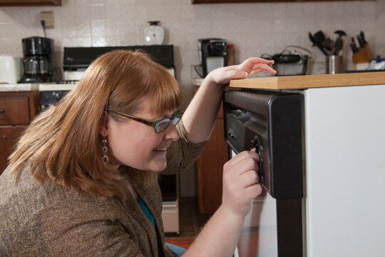Woman who is legally blind starting the dishwasher in her kitchen