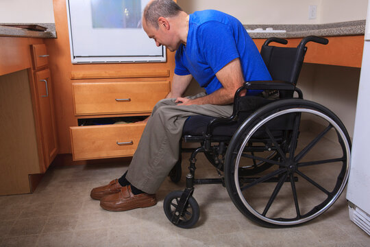 Man with Friedreich's Ataxia and deformed hands accessing items in a kitchen drawer