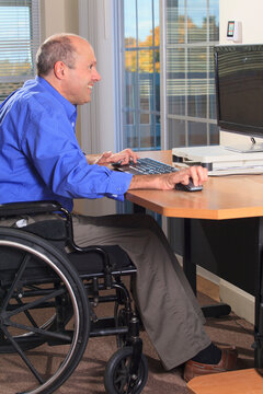 Man with Friedreich's Ataxia and deformed hands using his computer