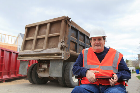 Construction engineer with spinal cord injury holding tablet on site