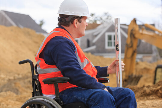 Construction engineer with spinal cord injury holding level at site