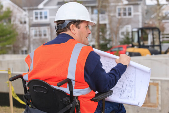 Construction engineer with spinal cord injury with house plans at construction site