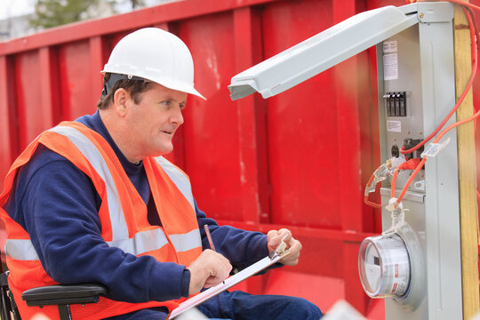 Construction engineer with spinal cord injury taking notes at temporary utility box