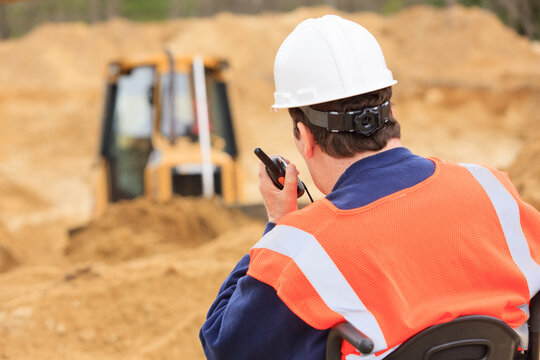 Construction engineer with spinal cord injury on radio to equipment operator