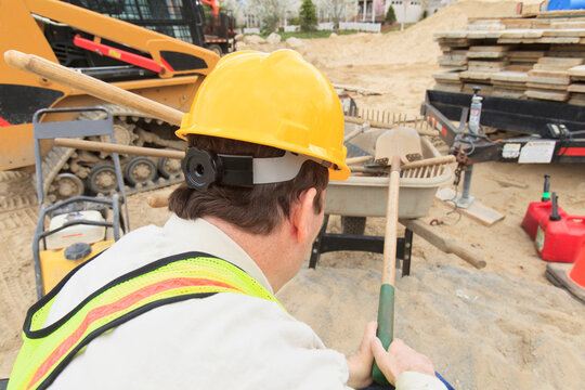 Construction supervisor with Spinal Cord Injury putting shovel into wheelbarrow