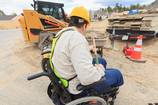 Construction supervisor with Spinal Cord Injury putting shovel into wheelbarrow