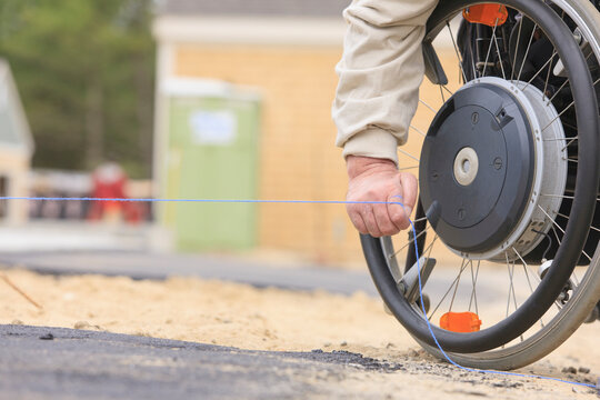 Construction supervisor with Spinal Cord Injury pulling chalkline at edge of pavement
