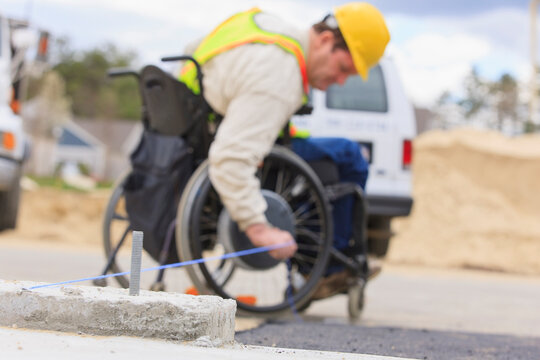 Construction supervisor with Spinal Cord Injury pulling chalkline at edge of pavement
