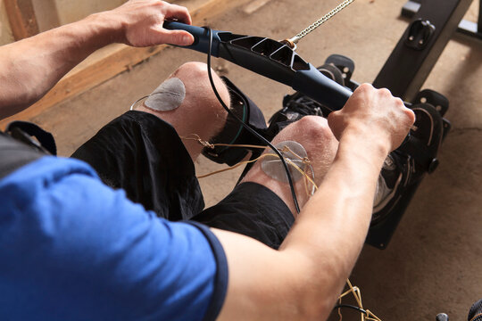 Man with spinal cord injury using his rowing machine with a muscle stimulator attached