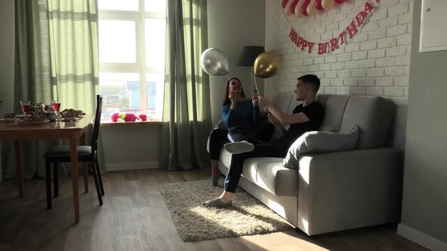 Mother and son fighting with balloons while sitting on the couch