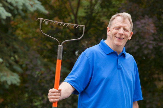 Man with Cerebral Palsy and dyslexia holding his rake