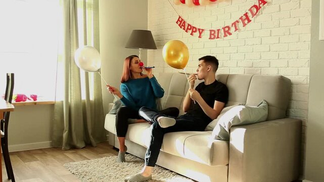Mother and son fighting with balloons while sitting on the couch