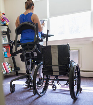 Woman with spinal cord injury working at home at her stand up desk
