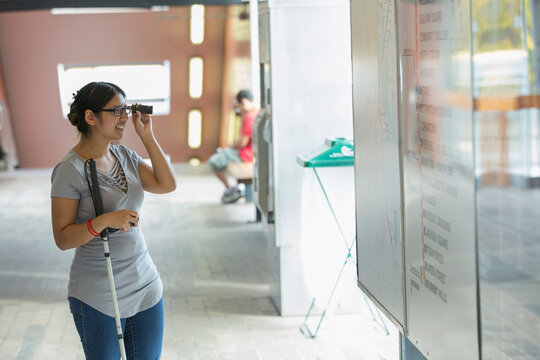 Woman with Visual Impairment using her cane and reading