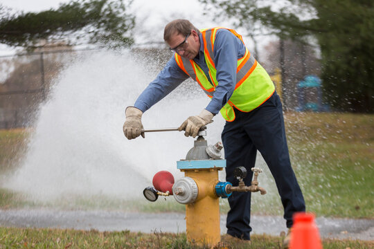 Water department technician opening fire hydrant to flush water pipes