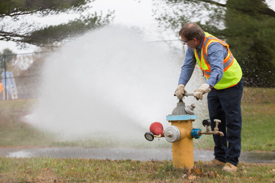 Water department technician opening fire hydrant to flush water pipes