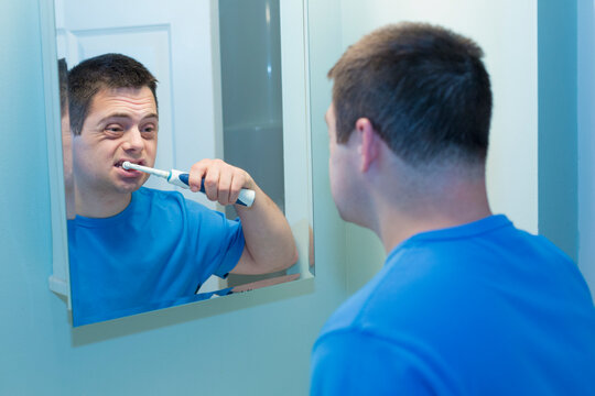 Man with Down Syndrome brushing teeth in bathroom