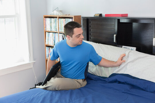 Man with Down Syndrome sitting on bed holding a laptop