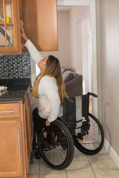 Woman with Spinal Cord Injury arranging things in her kitchen