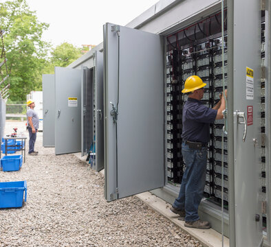 Engineers connecting energy storage batteries for back up power to an electric power plant