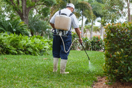 Pest control technician with portable spray rig using spray nozzle and hose