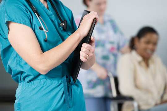 Midsection of a female nurse with stethoscope and file
