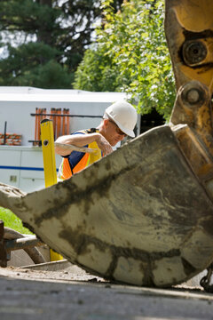 Worker at backhoe on construction site