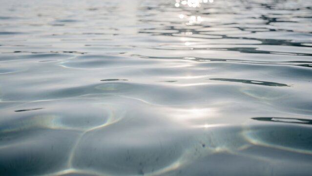 Stunning sunlit water surface with shimmering ripples and dynamic light reflections creating a serene tranquil natural background texture perfect for purity freshness and environmental concepts