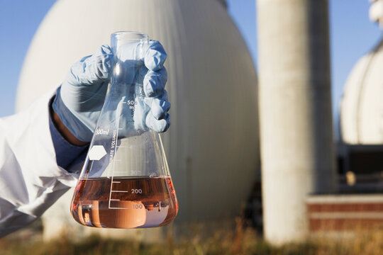 Scientist's hand holding a flask of water sample