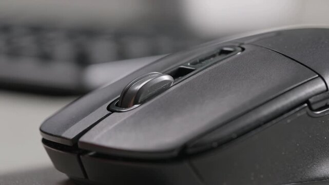 Finger scrolling on computer mouse wheel, close-up view of digital device interaction