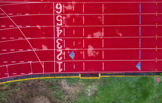 Aerial view of the red running track with white lane markings and numbers next to green grass at the Instituto Tecnologico de Merida, Yucatan, Mexico.