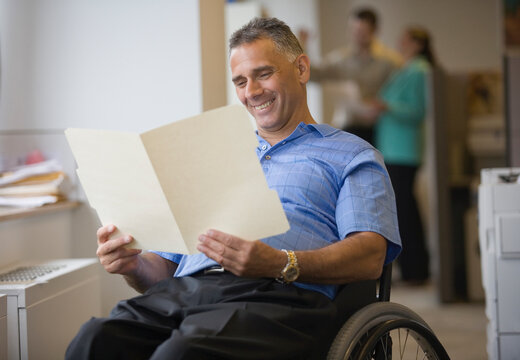Mid adult man sitting in a wheelchair and reading a document
